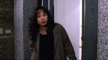 Movie still from “Vive L'Amour” (1994), directed by Tsai Ming-liang – A young woman with long black curly hair wearing a black shirt and a brown jacket; Close Up shot, High angle