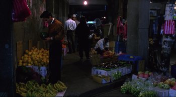Movie still from “Vive L'Amour” (1994), directed by Tsai Ming-liang – A group of people standing around a fruit stand; Wide shot, High angle