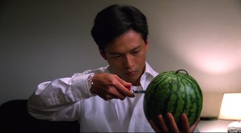 Movie still from “Vive L'Amour” (1994), directed by Tsai Ming-liang – A man cutting a watermelon with a knife; Close Up shot, High angle