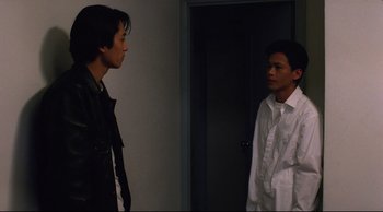 Movie still from “Vive L'Amour” (1994), directed by Tsai Ming-liang – Two men standing next to each other in front of a door; Medium shot, Over the shoulder angle