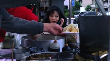 Movie still from “Vive L'Amour” (1994), directed by Tsai Ming-liang – A woman on a cell phone at an outdoor food market; Close Up shot, High angle
