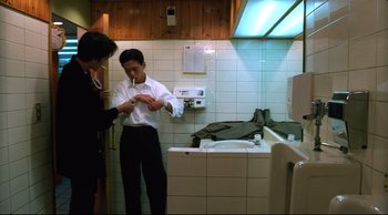 Movie still from “Vive L'Amour” (1994), directed by Tsai Ming-liang – A man in a white shirt and a man in a black shirt are in a bathroom; Medium shot, Low angle