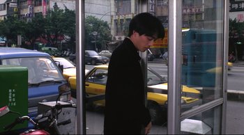 Movie still from “Vive L'Amour” (1994), directed by Tsai Ming-liang – A young man standing in front of a taxi cab; Medium shot, Over the shoulder angle