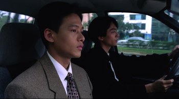 Movie still from “Vive L'Amour” (1994), directed by Tsai Ming-liang – Two men in suits sitting in the back seat of a car; Close Up shot, Low angle
