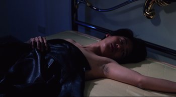 Movie still from “Vive L'Amour” (1994), directed by Tsai Ming-liang – A woman laying on a bed in a dark room; Medium shot, Overhead angle