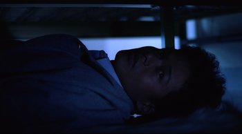 Movie still from “Vive L'Amour” (1994), directed by Tsai Ming-liang – A man laying down in a dark room at night; Medium shot, Overhead angle
