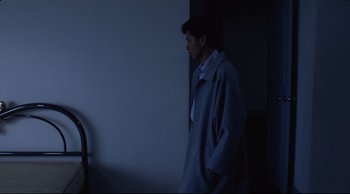 Movie still from “Vive L'Amour” (1994), directed by Tsai Ming-liang – A man standing in front of a wall in the dark; Medium shot, Over the shoulder angle