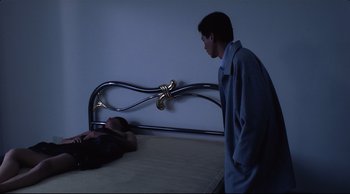 Movie still from “Vive L'Amour” (1994), directed by Tsai Ming-liang – A man standing next to a woman laying on a bed; Medium shot, High angle