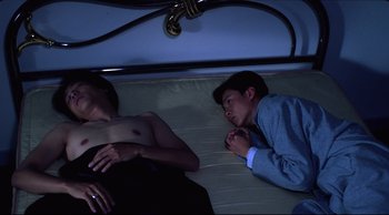 Movie still from “Vive L'Amour” (1994), directed by Tsai Ming-liang – Two people laying on a bed in the dark; Medium shot, High angle