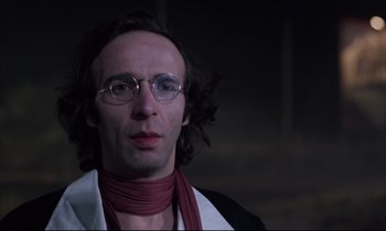Movie still from “Voice of the Moon” (1990), directed by Richard Stanley – A man wearing glasses and a red neck scarf; Close Up shot, Low angle