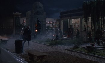 Movie still from “Voice of the Moon” (1990), directed by Richard Stanley – People are walking in a courtyard at night; Extreme Wide shot, High angle