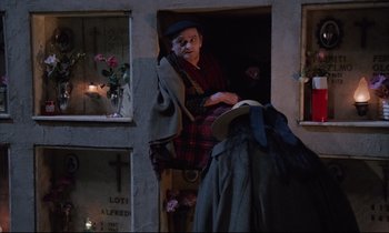 Movie still from “Voice of the Moon” (1990), directed by Richard Stanley – An old man sitting in a doorway next to a woman; Wide shot, High angle