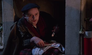 Movie still from “Voice of the Moon” (1990), directed by Richard Stanley – An old man sitting down with a knife and fork in his hand; Medium shot, High angle