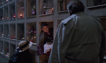 Movie still from “Voice of the Moon” (1990), directed by Richard Stanley – A man sitting in front of a window looking at another man standing next to him; Wide shot, High angle