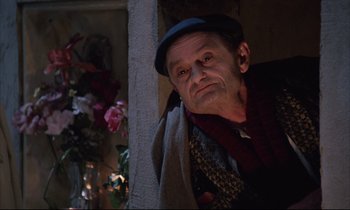 Movie still from “Voice of the Moon” (1990), directed by Richard Stanley – An old man wearing a hat and a scarf; Close Up shot, Low angle