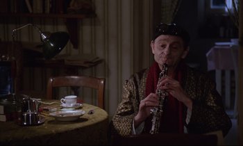 Movie still from “Voice of the Moon” (1990), directed by Richard Stanley – An older man playing a clarinet in a restaurant; Medium shot, High angle