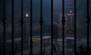 Movie still from “Voice of the Moon” (1990), directed by Richard Stanley – An old man standing in front of a fence; Wide shot, High angle