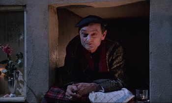 Movie still from “Voice of the Moon” (1990), directed by Richard Stanley – An old man sitting in a corner with a cigarette in his mouth; Medium shot, Low angle