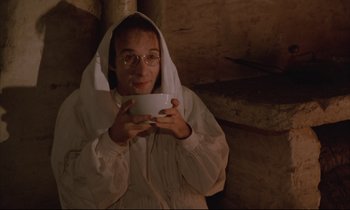 Movie still from “Voice of the Moon” (1990), directed by Richard Stanley – A man in a white robe holding a white bowl; Medium shot, High angle