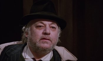 Movie still from “Voice of the Moon” (1990), directed by Richard Stanley – An older man wearing a black hat and a white shirt; Close Up shot, Low angle