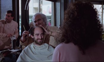 Movie still from “Voice of the Moon” (1990), directed by Richard Stanley – A man getting his hair combed by a woman; Medium shot, Over the shoulder angle