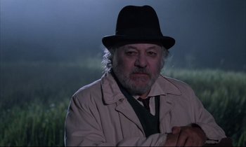 Movie still from “Voice of the Moon” (1990), directed by Richard Stanley – An older man wearing a hat and a jacket; Close Up shot, Over the shoulder angle