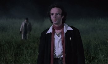 Movie still from “Voice of the Moon” (1990), directed by Richard Stanley – A man in a black jacket and a red scarf; Medium shot, Low angle