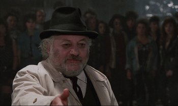 Movie still from “Voice of the Moon” (1990), directed by Richard Stanley – An older man wearing a hat and a coat; Close Up shot, Over the shoulder angle