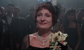Movie still from “Voice of the Moon” (1990), directed by Richard Stanley – A person wearing a black dress; Close Up shot, Over the shoulder angle