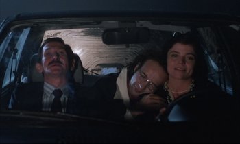 Movie still from “Voice of the Moon” (1990), directed by Richard Stanley – A group of people in the back seat of a car; Medium shot, Low angle