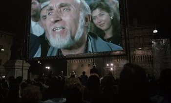 Movie still from “Voice of the Moon” (1990), directed by Richard Stanley – People watching a movie on a big screen; Close Up shot, Over the shoulder angle