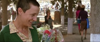 Movie still from “Volver” (2006), directed by Pedro Almodóvar – A woman holding a bouquet of flowers outside; Medium shot, Over the shoulder angle