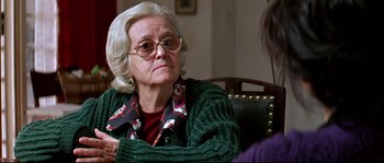Movie still from “Volver” (2006), directed by Pedro Almodóvar – An older woman sitting in a chair with her hands crossed; Close Up shot, Over the shoulder angle