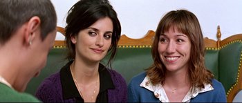 Movie still from “Volver” (2006), directed by Pedro Almodóvar – Two women smile for the camera while posing for a picture; Close Up shot, Over the shoulder angle