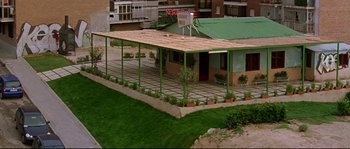 Movie still from “Volver” (2006), directed by Pedro Almodóvar – An outdoor area with a basketball hoop and a green roof; Extreme Wide shot, High angle