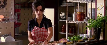 Movie still from “Volver” (2006), directed by Pedro Almodóvar – A woman in an apron cutting food in a kitchen; Medium shot, Low angle