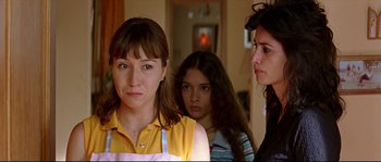 Movie still from “Volver” (2006), directed by Pedro Almodóvar – Three women are standing in a room and one is looking at the camera; Close Up shot, Over the shoulder angle