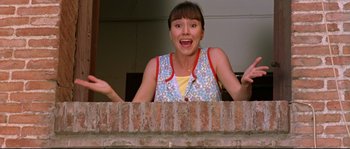 Movie still from “Volver” (2006), directed by Pedro Almodóvar – A woman standing in front of a brick wall with her mouth wide open; Medium shot, Low angle