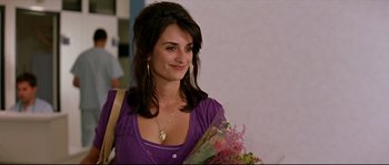 Movie still from “Volver” (2006), directed by Pedro Almodóvar – A woman in a purple shirt holding a bouquet of flowers; Close Up shot, Over the shoulder angle