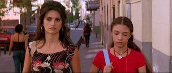Movie still from “Volver” (2006), directed by Pedro Almodóvar – Two young women walking down a sidewalk near a building; Close Up shot, Low angle