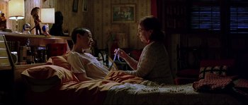 Movie still from “Volver” (2006), directed by Pedro Almodóvar – An older woman is holding a toothbrush while a younger man lies in a bed; Medium shot, High angle