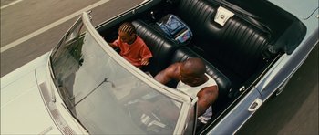 Movie still from “Waist Deep” (2006), directed by Vondie Curtis-Hall – A man and a boy sitting in the back seat of a car; Wide shot, High angle
