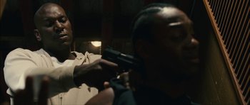 Movie still from “Waist Deep” (2006), directed by Vondie Curtis-Hall – A man holding a gun in a room; Close Up shot, Over the shoulder angle