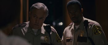 Movie still from “Waist Deep” (2006), directed by Vondie Curtis-Hall – Two police officers standing next to each other in the dark; Close Up shot, Over the shoulder angle