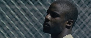 Movie still from “Waist Deep” (2006), directed by Vondie Curtis-Hall – A person with a chain link fence in the background; Close Up shot, Low angle