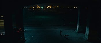 Movie still from “Waist Deep” (2006), directed by Vondie Curtis-Hall – A man standing on the ground in a dark parking lot at night; Extreme Wide shot, High angle