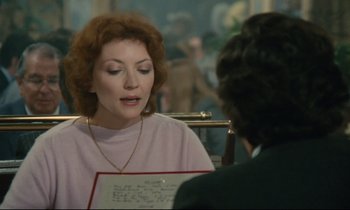 Movie still from “Waiter!” (1983), directed by Claude Sautet – A woman sitting in front of a man holding a piece of paper; Close Up shot, Over the shoulder angle