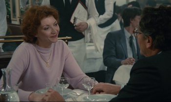 Movie still from “Waiter!” (1983), directed by Claude Sautet – A woman sitting at a table with a glass of wine in front of a man; Medium shot, Over the shoulder angle