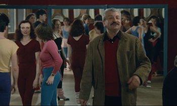 Movie still from “Waiter!” (1983), directed by Claude Sautet – An older man is standing in front of a group of people; Medium shot, Low angle