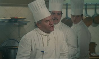 Movie still from “Waiter!” (1983), directed by Claude Sautet – A group of men in chef's hats standing in a kitchen; Medium shot, High angle